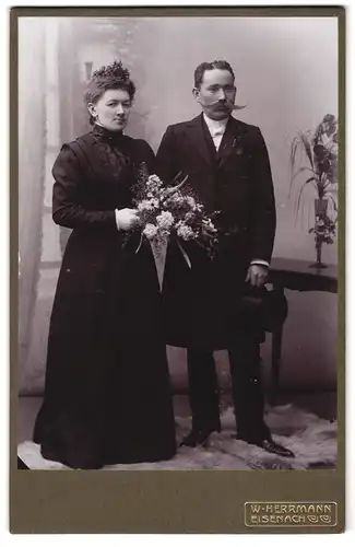 Fotografie W. Herrmann, Eisenach, Karlstrasse 6, Portrait bürgerliches Paar in hübscher Kleidung mit Blumenstrauss