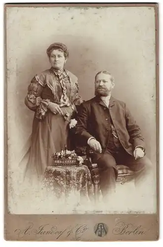 Fotografie A. Jandorf & Co., Berlin-N, Brunnen-Strasse 19-21, Portrait bürgerliches Paar mit Blumen am Tisch