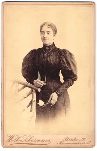 Fotografie Wilh. Scharmann, Berlin-SW, Kommandantenstrasse 15, Portrait bürgerliche Dame mit Blume an Zaun gelehnt