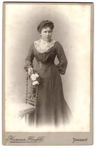 Fotografie Hermann Herzfeld, Dresden-A, Portrait bürgerliche Dame mit Blumen an Stuhl gelehnt