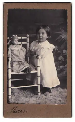Fotografie Fotograf und Ort unbekannt, niedliches Mädchen lässt Puppe auf dem Stuhl sitzen