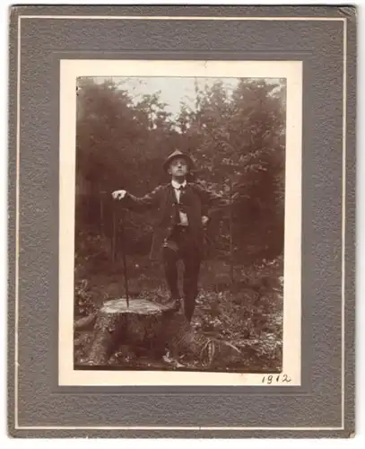Fotografie Fotograf und Ort unbekannt, Knabe in Lederhose am Baumstumpf posierend