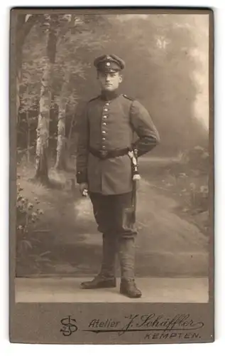 Fotografie Atelier J. Schäffer, Kempten, Portrait bayrischer Soldat in Uniform mit Bajonett und Portepee, Feldmütze