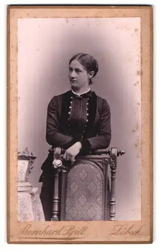 Fotografie Bernhard Prill, Lübeck, Breite-Strasse 35, Portrait bürgerliche Dame mit Blume an Stuhl gelehnt