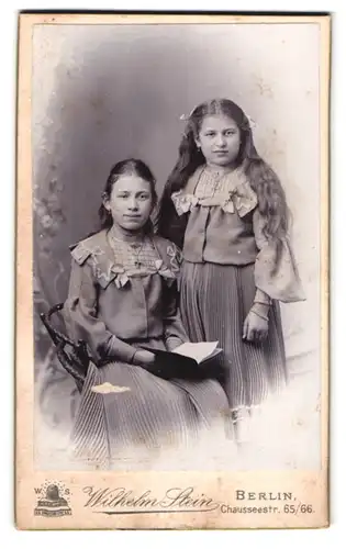 Fotografie Wilhelm Stein, Berlin, Chausseestrasse 65-66, Portrait zwei junge Mädchen in hübscher Kleidung mit Buch