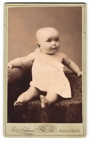 Fotografie Robert Ochernal, Marienberg i / S., Portrait niedliches Baby im weissen Hemd mit nackigen Füssen