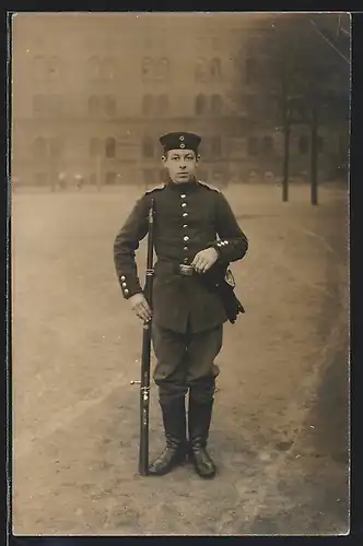 Foto-AK Soldat in Uniform mit Gewehr bei Fuss und Krätzchen