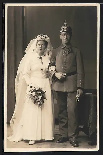 Foto-AK preussischer Soldat in Feldgrau Uniform mit Pickelhaube nebst seiner Frau, Kriegshochzeit, Orden