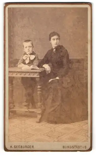 Fotografie H. Seeburger, Burgstädt i. S., Bahnhofstrasse, Junge Mutter in schwarz posiert mit ihrem süssen Jungen