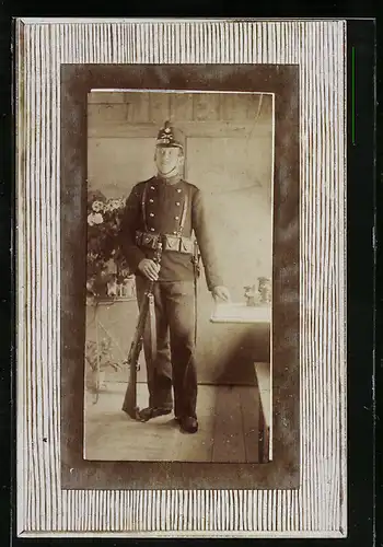 Foto-AK Soldat in Uniform mit Gewehr in einem Privatraum
