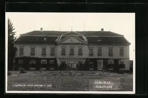 AK Dukowan, Blick auf ein grosses Gebäude mit Parkanlage