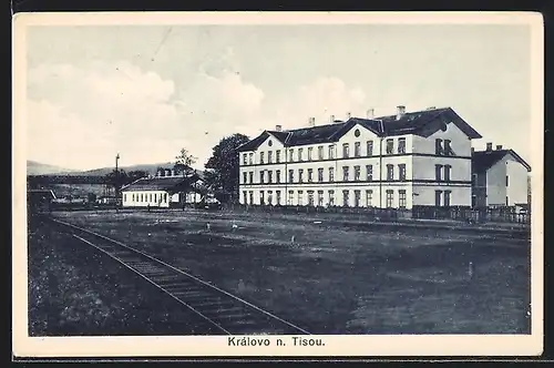 AK Královo n. Tisou, Blick über die Eisenbahnschienen auf ein grosses Gebäude