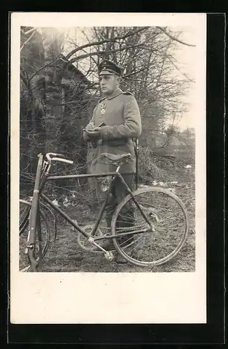 Foto-AK Soldat steht mit seinem Notizbuch neben einem Fahrrad, Uniformfoto