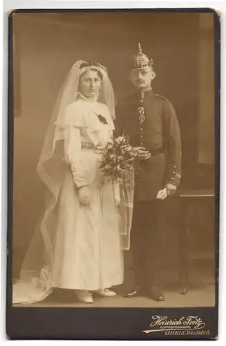 Fotografie Heinrich Fritz, Greiz, Uffz. in Uniform mit Pickelhaube und Eisernes Kreuz nebst Braut, Kriegshochzeit