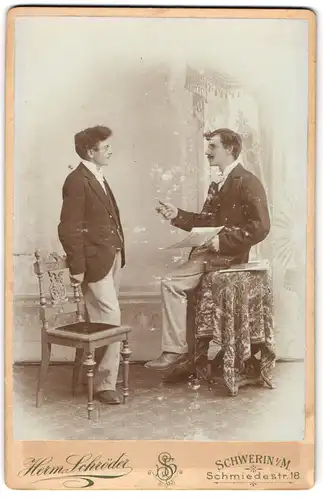 Fotografie Herm. Schröder, Schwerin i. M., zwei junge Herren beim Diskutieren im Atelier