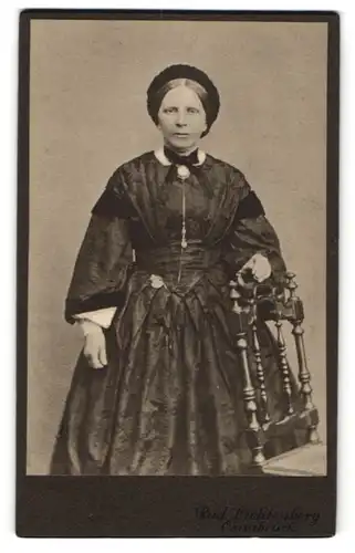 Fotografie Rud. Lichtenberg, Osnabrück, Möserstr. 24, Dame im dunklen gemusterten Kleid mit Brosche