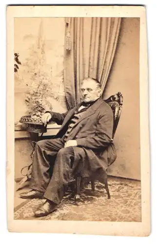 Fotografie unbekannter Fotograf und Ort, Herr Hofmann aus Eisenberg im Anzug sitzend im Stuhl