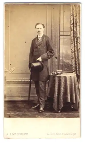 Fotografie A. J. Melhuish, London, englischer Herr im Anzug mit Zylinder und Schirm vor einer Studiokulisse