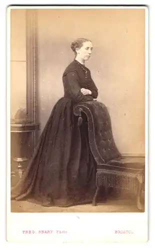 Fotografie Fred. Snary, Bristol, junge Frau im dunklen Kleid lehnt an einem Sessel