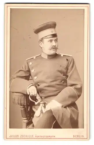 Fotografie Julius Zschille, Berlin, Soldat in Uniform mit höher Mütze und Säbel