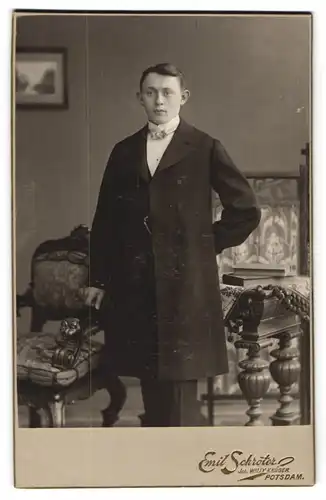Fotografie Emil Schröter, Potsdam, Schloss-Str. 1-3, Junger hübscher Mann mit abstehenden Ohren im schwarzen Mantel