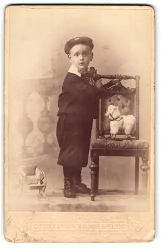 Fotografie Otto Lindner, Berlin, junger Knabe im Anzug mit Spielzeug Ziege auf dem Stuhl