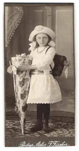 Fotografie F. Fischer, Ort unbekannt, junges Mädchen zur Einschulung mit Schulranzen und Zuckertüte, erster Schultag