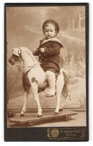 Fotografie A. Jandorf & Co., Berlin, junger Knabe auf seinem Schaukelpferd auf Rollen im Atelier