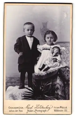 Fotografie Rud. Lichtenberg, Osnabrück, zwei niedliche kleine Kinder im Anzug und Kleid mit grosser Puppe im Arm