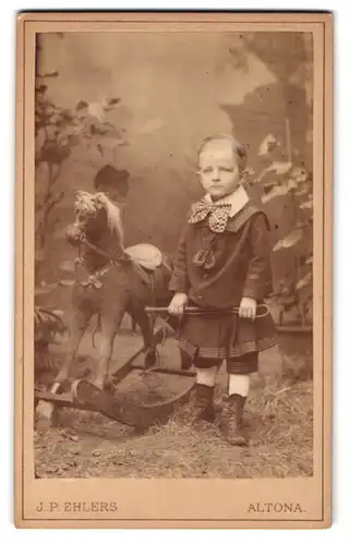 Fotografie J. P. Ehlers, Altona, junger Knabe im Kleid mit seinem Schaukelpferd