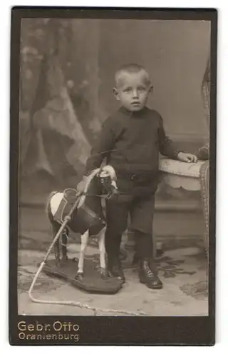 Fotografie Gebr. Otto, Oranienburg, junger Knabe nebst seinem Schaukelpferd und Reitgerte