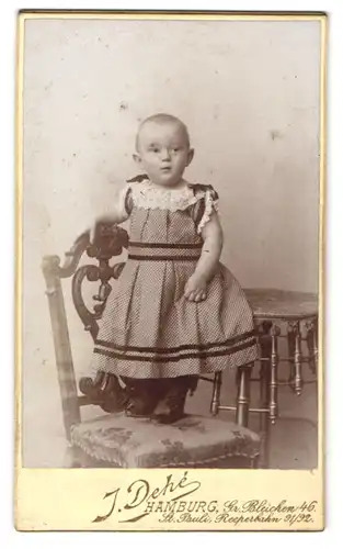 Fotografie J. Dehe, Hamburg, Gr. Bleichen 46, Niedliches Kleinkind im Kleid steht auf Stuhl