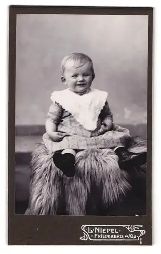 Fotografie L. Niepel, Friedeberg a. Qu., Süsses Kleinkind im Kleid lacht erfreut