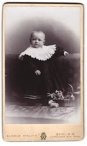 Fotografie Globus Atelier, Berlin, Leipziger Str. 132, Niedliches Kleinkind im weiten schwarzen Kleid mit Blumenkorb
