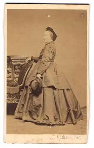 Fotografie H. Mathaus, München, Schwanthalerstr. 4, Ältere Dame im weiten hellen Kleid mit Hut im Profil