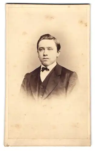 Fotografie A. H. Heckmann, Osnabrück, Johannesst. 68, Junger Mann im schwarzen Anzug mit Fliege und Seitenscheitel