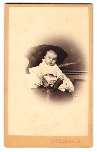 Fotografie E. von Pleschner, Graz, Mettahof Str. 8, Niedliches Baby im weissen Kleid hält mit offenem Mund die Füsse fest
