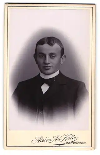 Fotografie Ad. Kolle, Göttingen, Schneidiger junger Mann im schwarzen Anzug mit Mittelscheitel und Kinngrübchen
