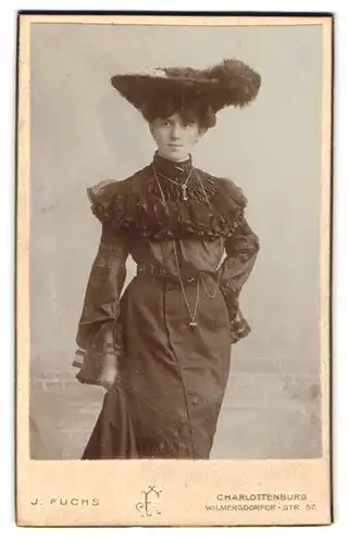 Fotografie J. Fuchs, Berlin-Charlottenburg, junge Dame im dunklen Kleid mit breitem Federhut, Kette mit Herzanhänger