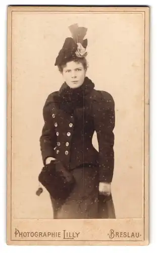 Fotografie Lilly, Breslau, junge Dame im tailierten Winterkleid mit Muff und Feder an der Mütze