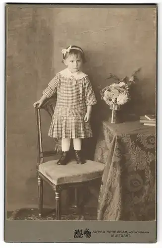 Fotografie Alfred Hirrlinger, Stuttgart, niedliches kleines Mädchen im karierten Sommerkleid mit Haarschleife auf Stuhl