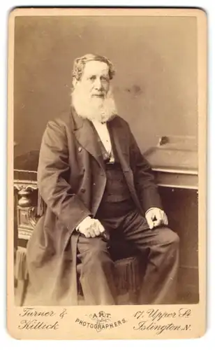 Fotografie Turner & Killick, London-Islington, älterer Herr im Anzug mit weissem Vollbart sitzend am Sekretär