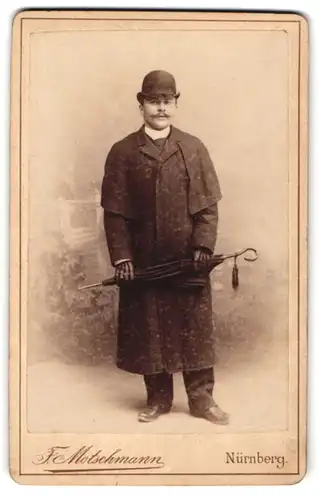 Fotografie F. Motschmann, Nürnberg, junger Mann im Mantel mit Schirm und Melone