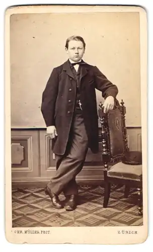 Fotografie Chr. Müller, Zürich, junger Knabe im Anzug mit Fliege nebst Hut auf dem Stuhl
