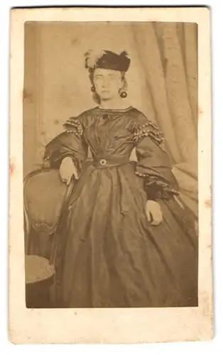 Fotografie L. J. Lekeu, Verviers, junge Frau im dunklen Kleid mit Federhut und Ohrringen