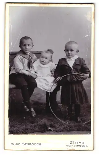 Fotografie Hugo Schröder, Zittau, Milchstr. 7, Niedliche Geschwisterkinder in Kleidern und Matrosenhemd mit Reifen