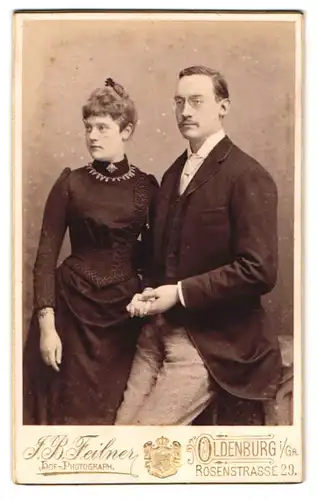 Fotografie J. P. Feilner, Oldenburg, Rosenstr. 29, Eleganter Herr mit Kneifer hält liebevoll die Hand seiner Gattin
