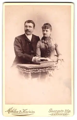 Fotografie Möhler & Knirim, Hannover, Georgstr. 25p, Hübsches Paar in vertrauter Pose, Herr mit Kneifer und Schnauzer