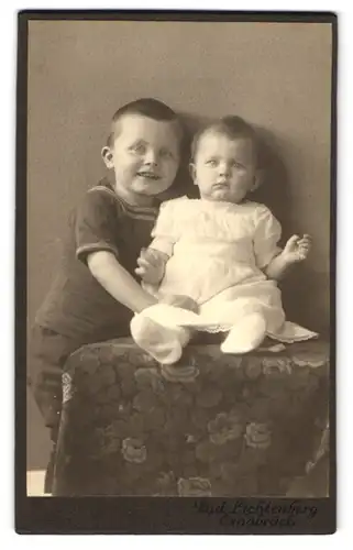 Fotografie Rud. Lichtenberg, Osnabrück, Lächelnder süsser Junge mit seiner kleinen Schwester die entsetzt blickt