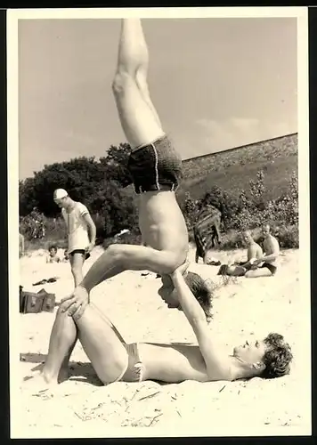 Fotografie sportliche Burschen in Badehose machen akrobatische Übungen am Badestrand